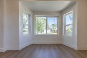 Bay window configuration with three large windows, light-tone wall paint, wood-finish flooring, and white trim throughout