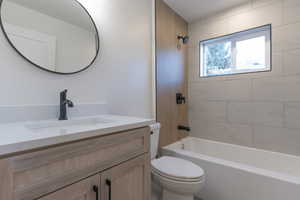 Bathroom featuring a light wood-finish vanity with an integrated sink and matte black faucet, a round black-framed mirror, white rectangular wall tiles, a bathtub with a matte black shower fixture, and a window
