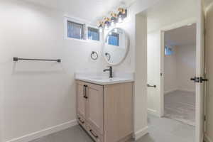 Bathroom vanity featuring light wood cabinetry, quartz countertop, and matte black fixtures