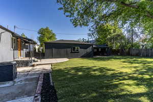 Expansive backyard featuring a manicured lawn, concrete patio, and mature trees
