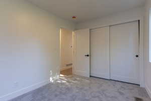 Room featuring light gray carpet flooring, white walls, and a white sliding closet door