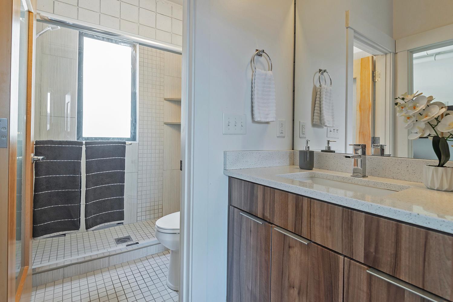 Bathroom vanity featuring a wood-finish cabinet with chrome hardware, an integrated rectangular sink, and a speckled light-toned countertop