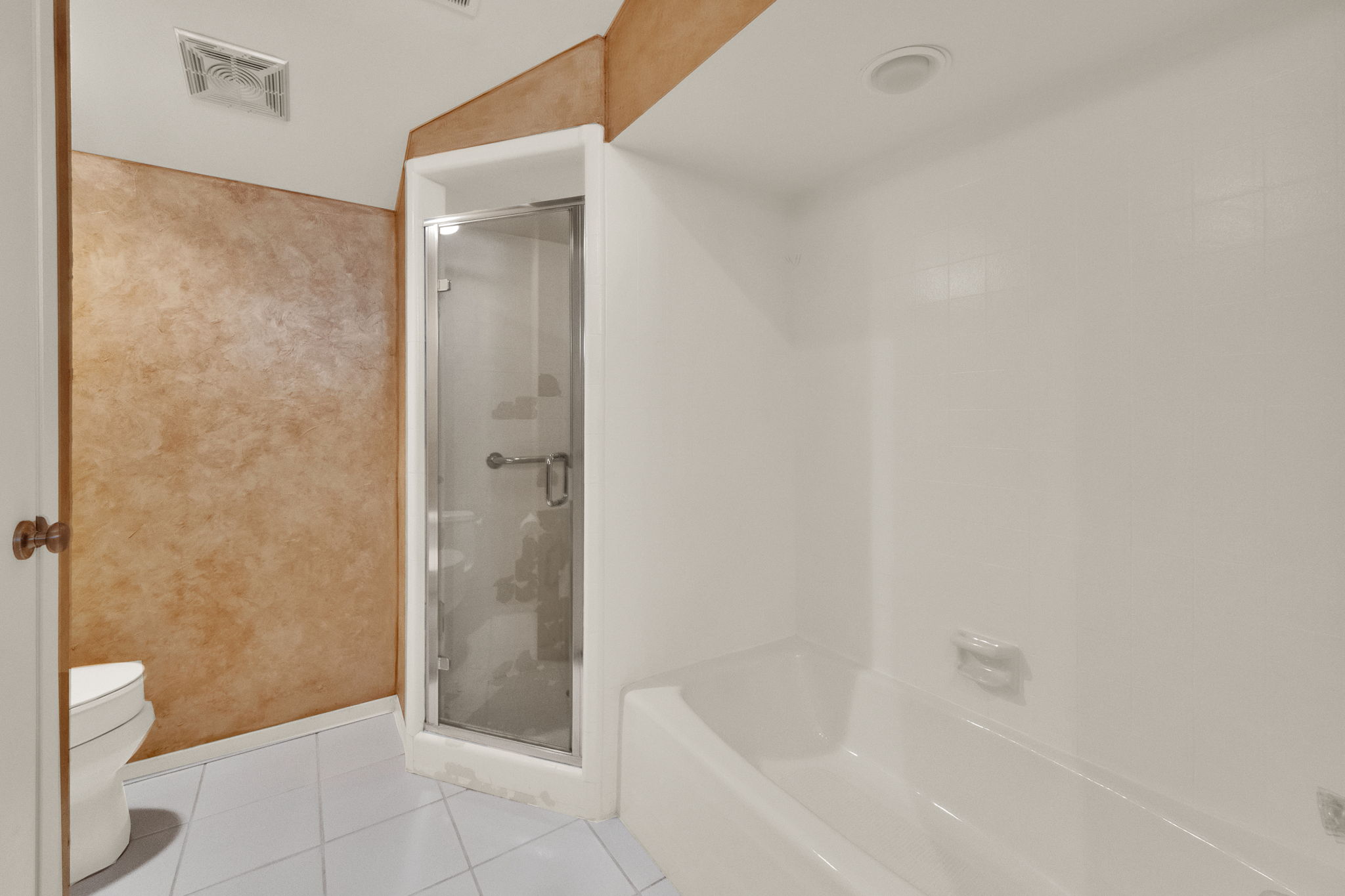 Bathroom featuring a built-in shower with a glass enclosure, white bathtub, light-colored tile flooring, and textured wall finishes