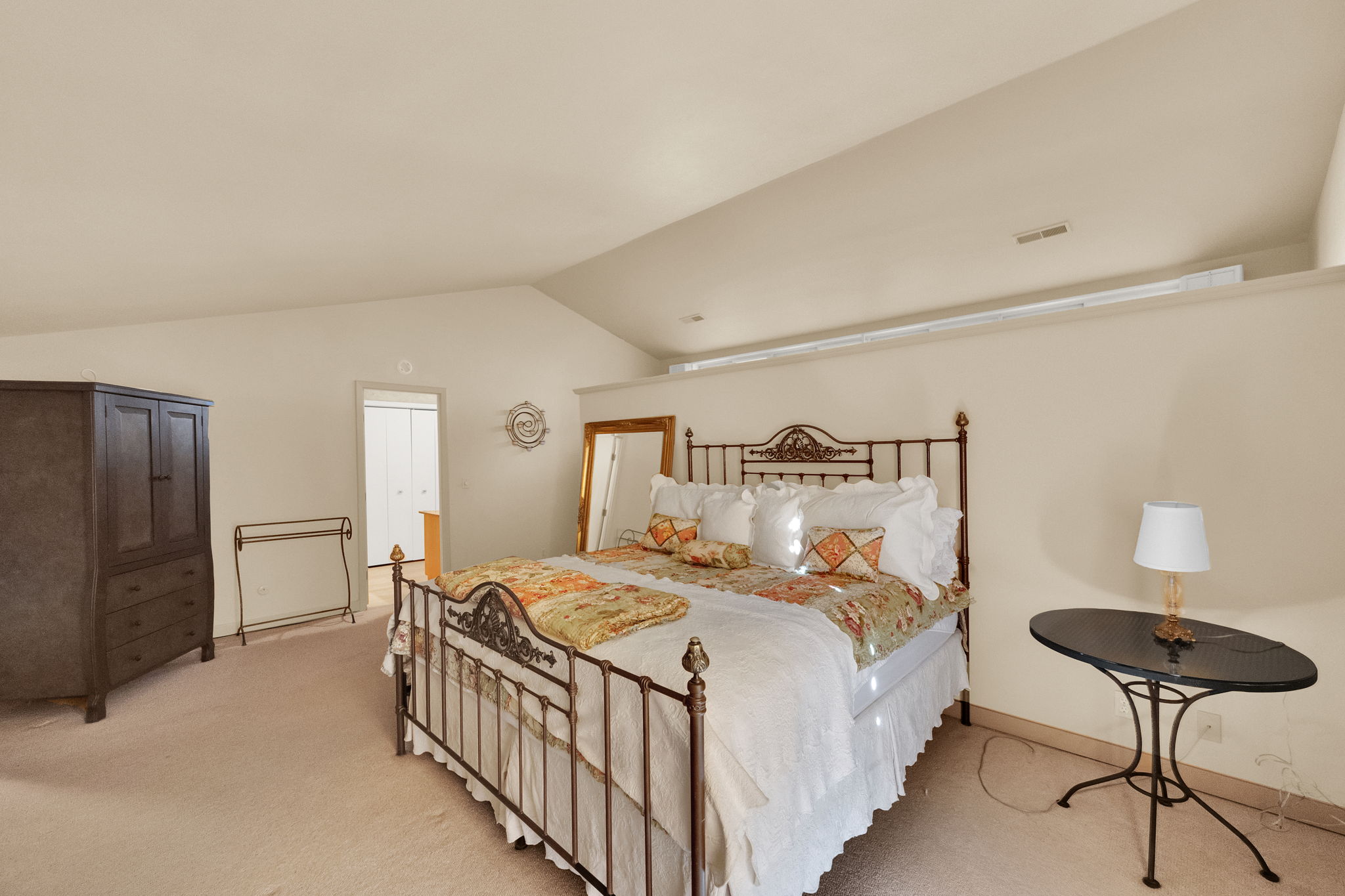 Carpeted room with a vaulted ceiling and a high shelf feature