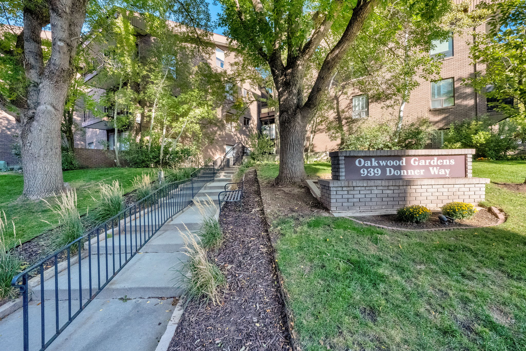 Oakwood Gardens property sign set in a landscaped area with mature trees and green lawns