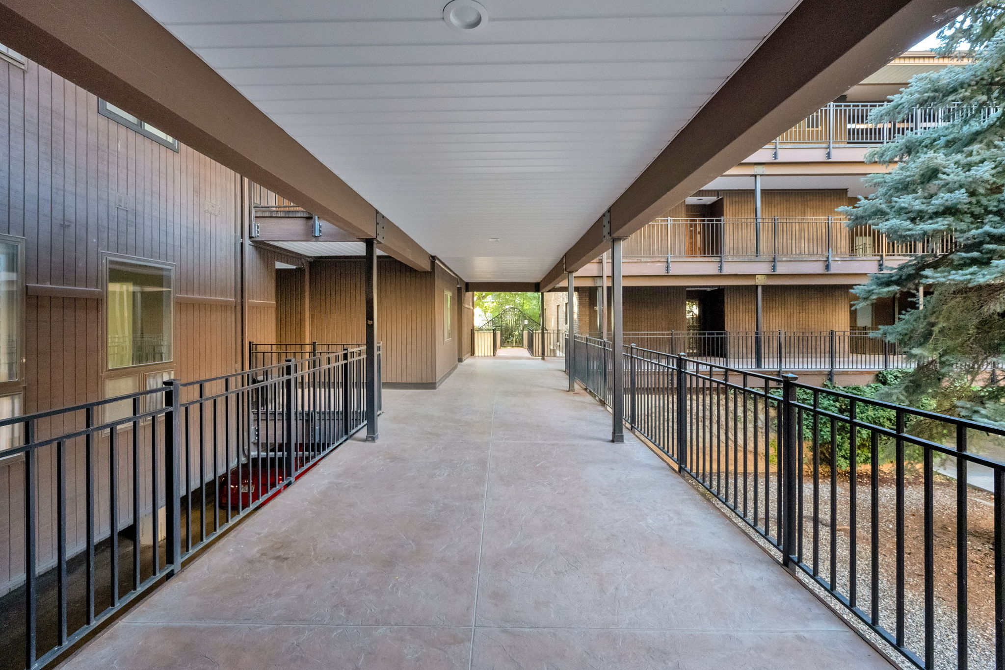 Covered exterior walkway featuring a concrete surface and black metal railings