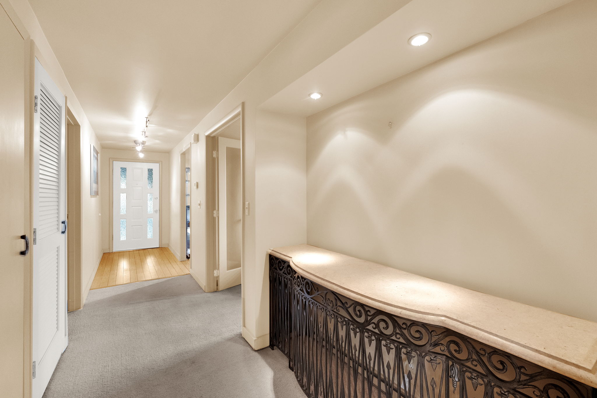 Foyer featuring a decorative wrought iron console with a light-colored countertop, recessed lighting, track lighting, a white paneled entry door with frosted glass inserts, and a combination of carpet and wood-finish flooring