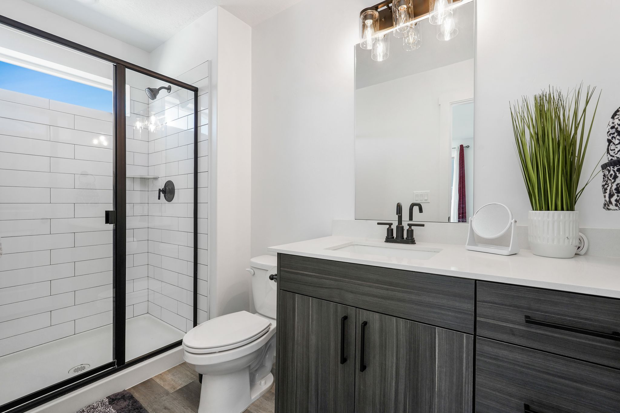 Modern bathroom featuring a walk-in shower with subway tile surround and black-framed glass enclosure