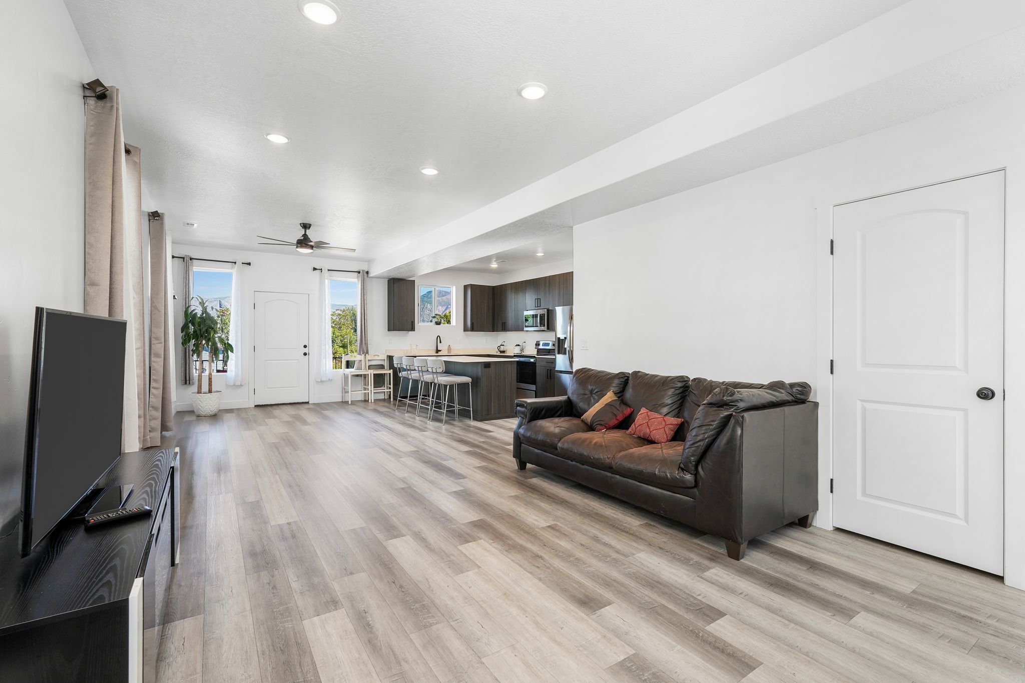 Open-concept living space featuring wood-finish flooring, recessed lighting, and a ceiling fan