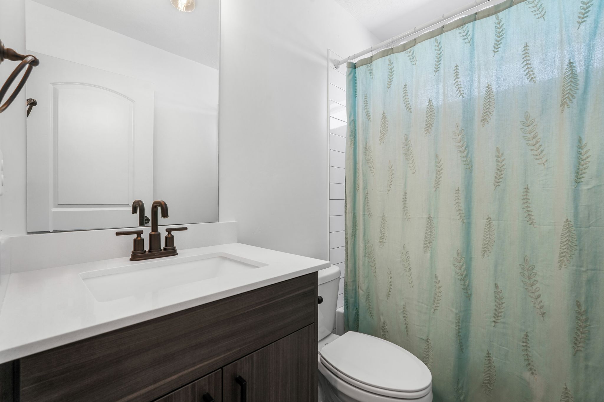 White vanity with integrated sink, dark wood-finish cabinetry, and oil-rubbed bronze faucet