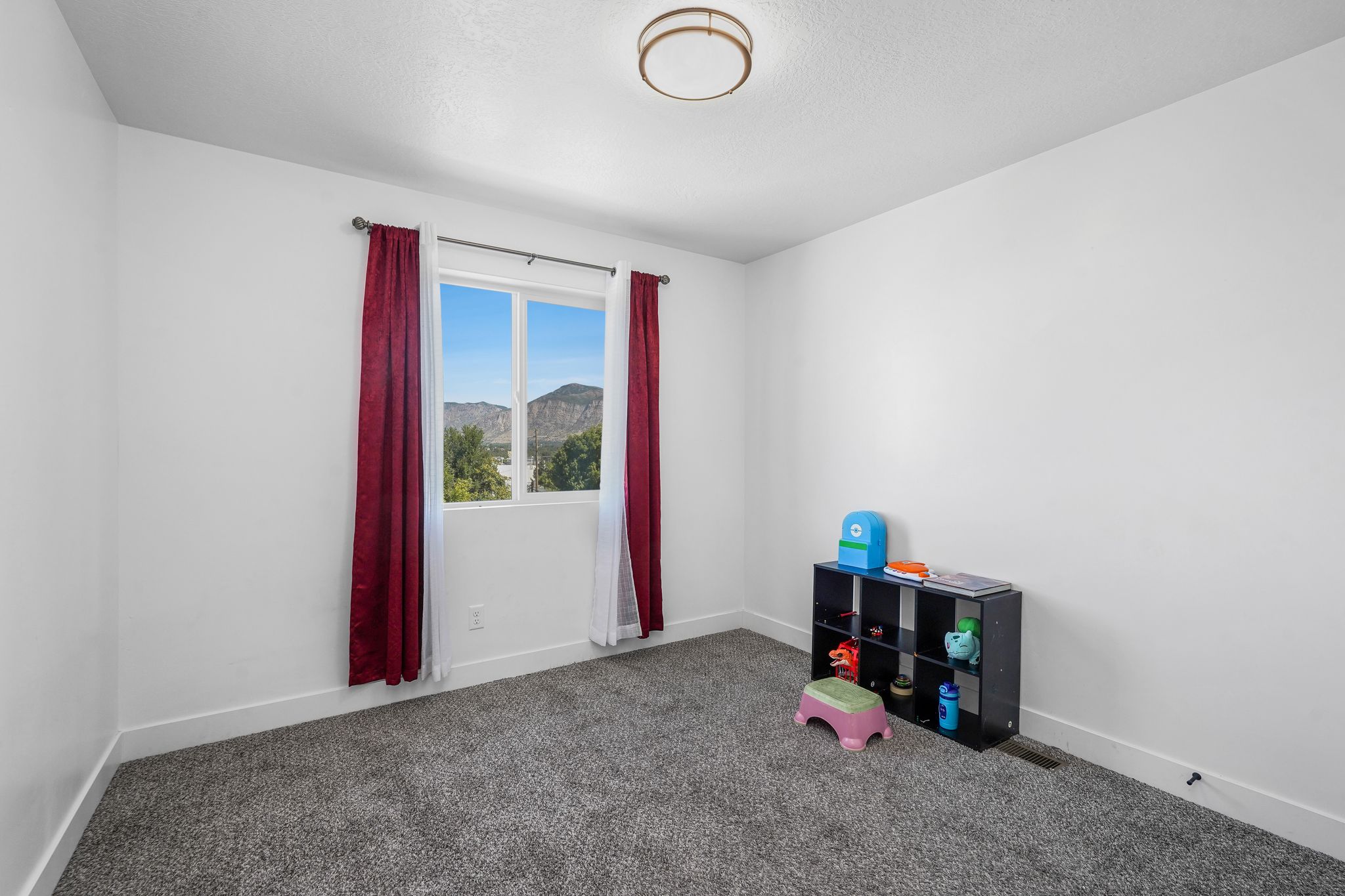 Bedroom featuring a double window with mountain scenery, neutral carpeting, white walls, and a contemporary ceiling light fixture