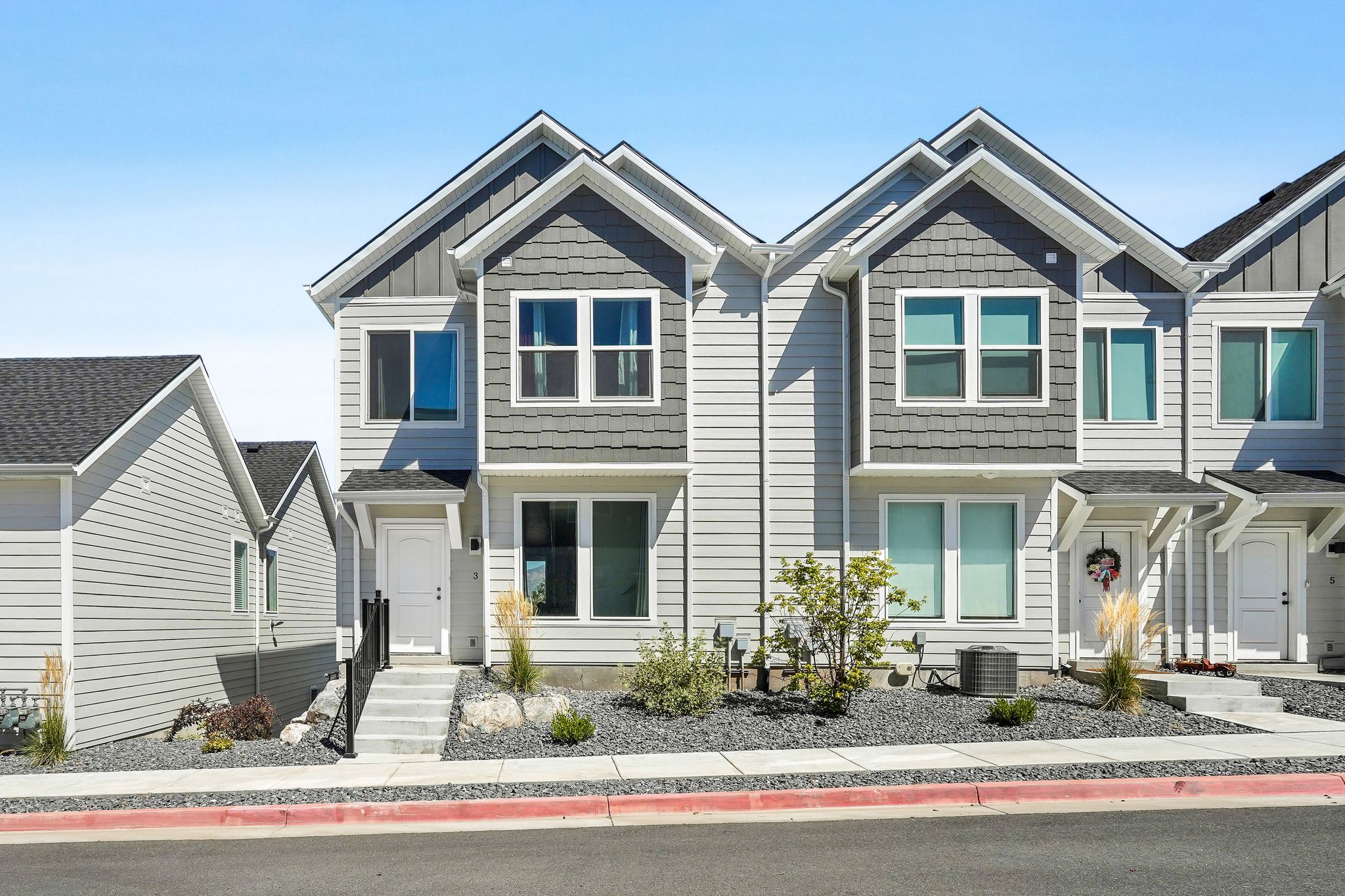 Contemporary multi-story exterior featuring light gray siding and dark gray shake accents