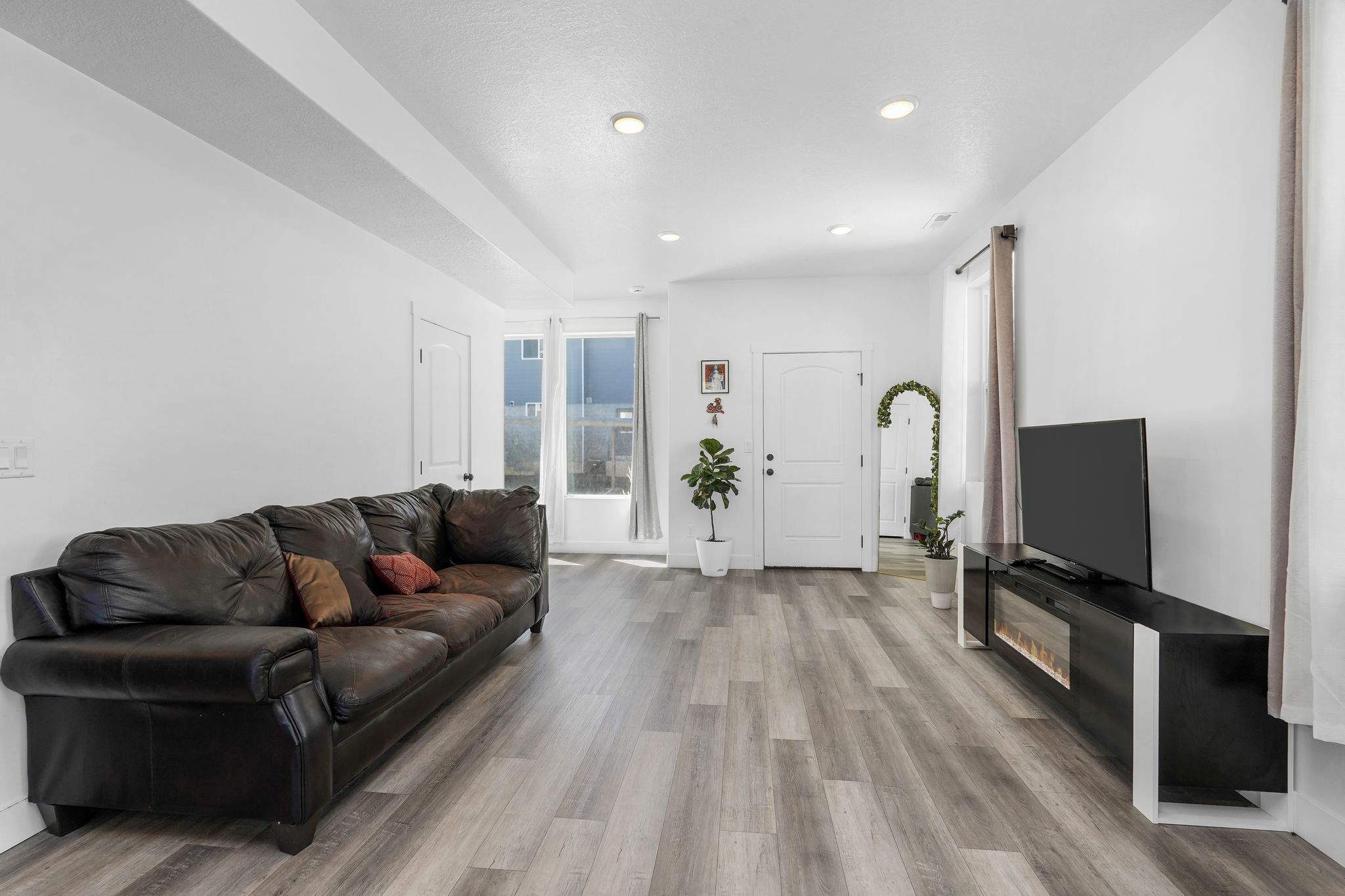 Spacious living area featuring wood-finish flooring, recessed lighting, and white walls