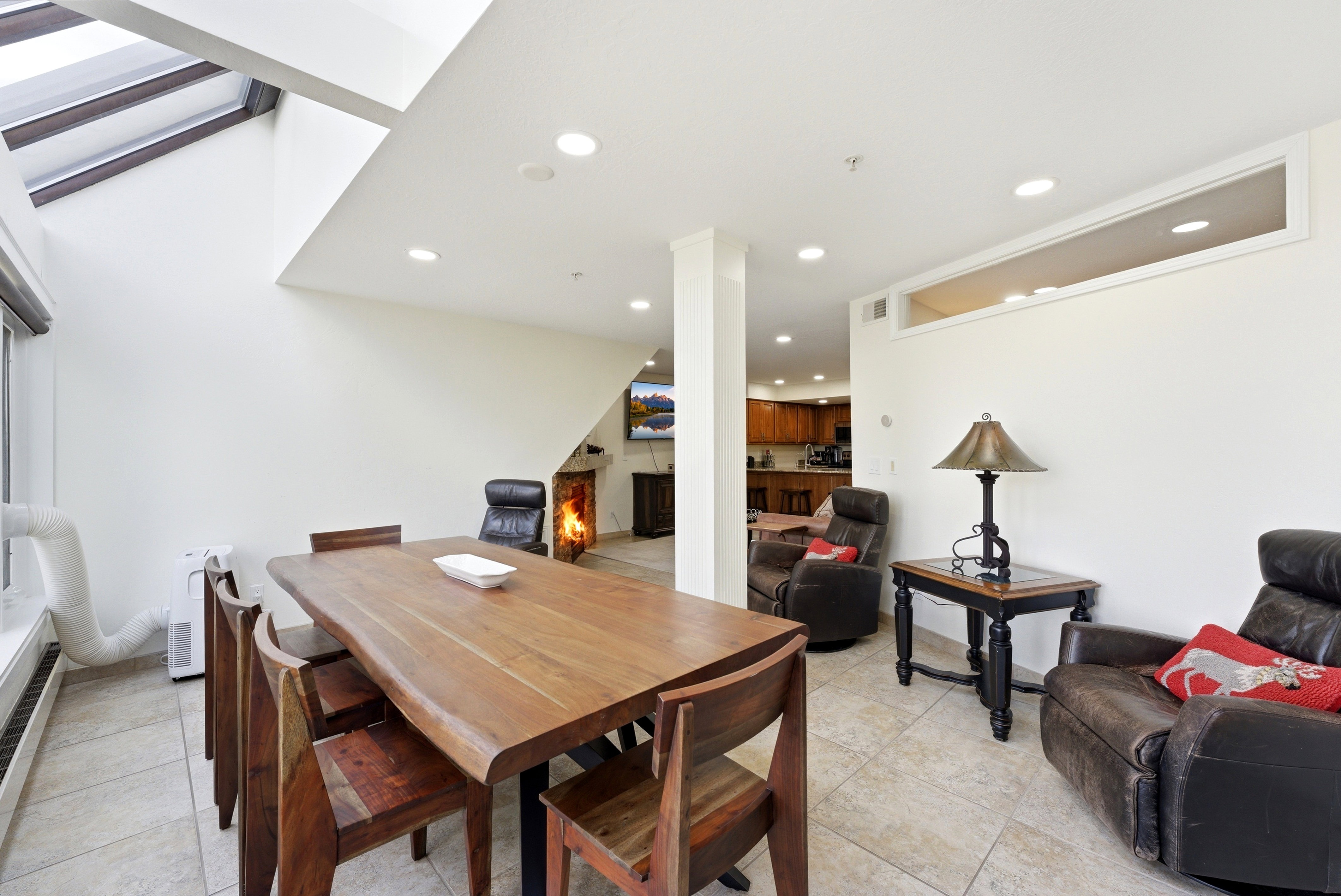 Dining area with a warm lit fireplace, light tile patterned floors, and recessed lighting