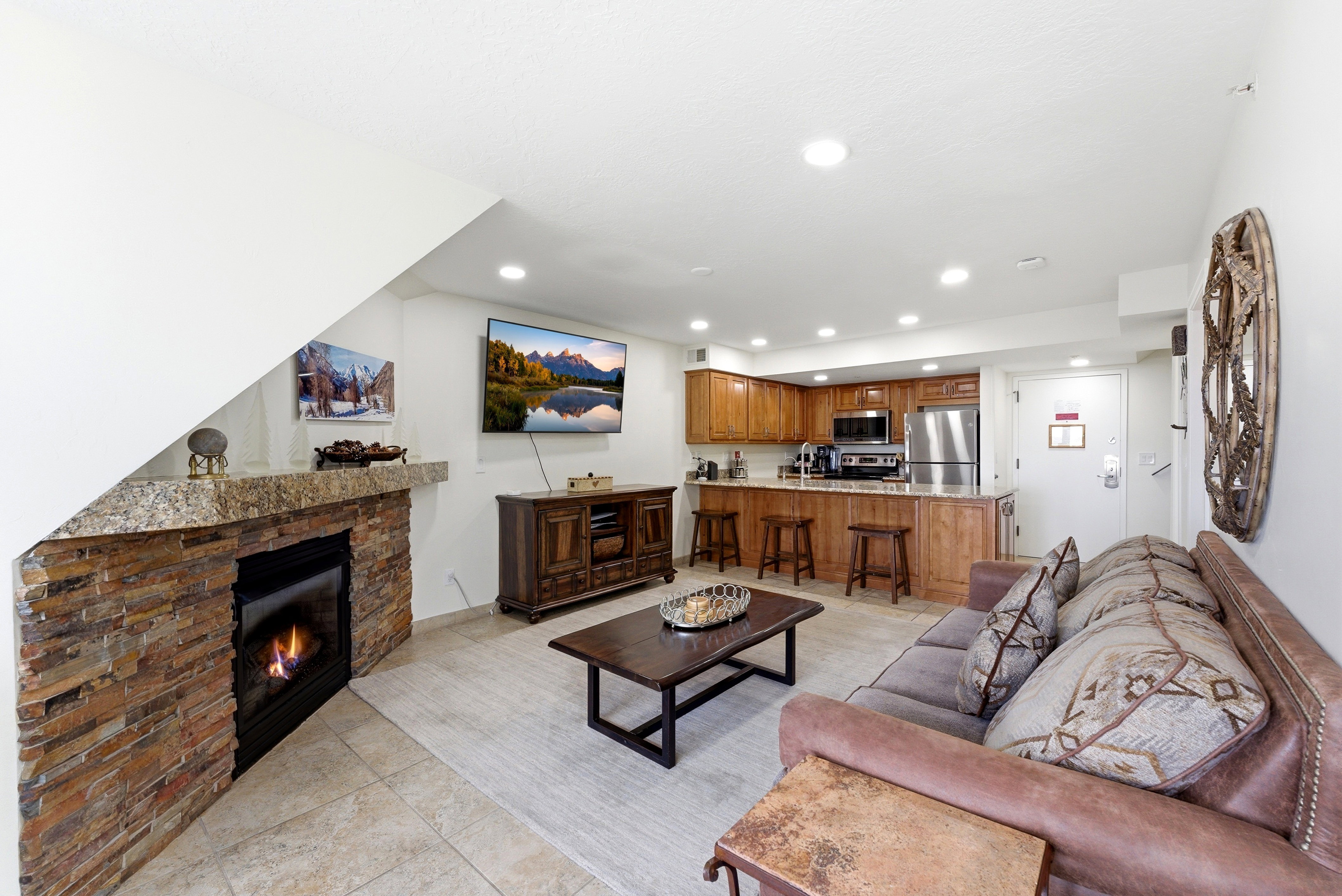 Living room with a stone fireplace, light tile patterned flooring, and recessed lighting
