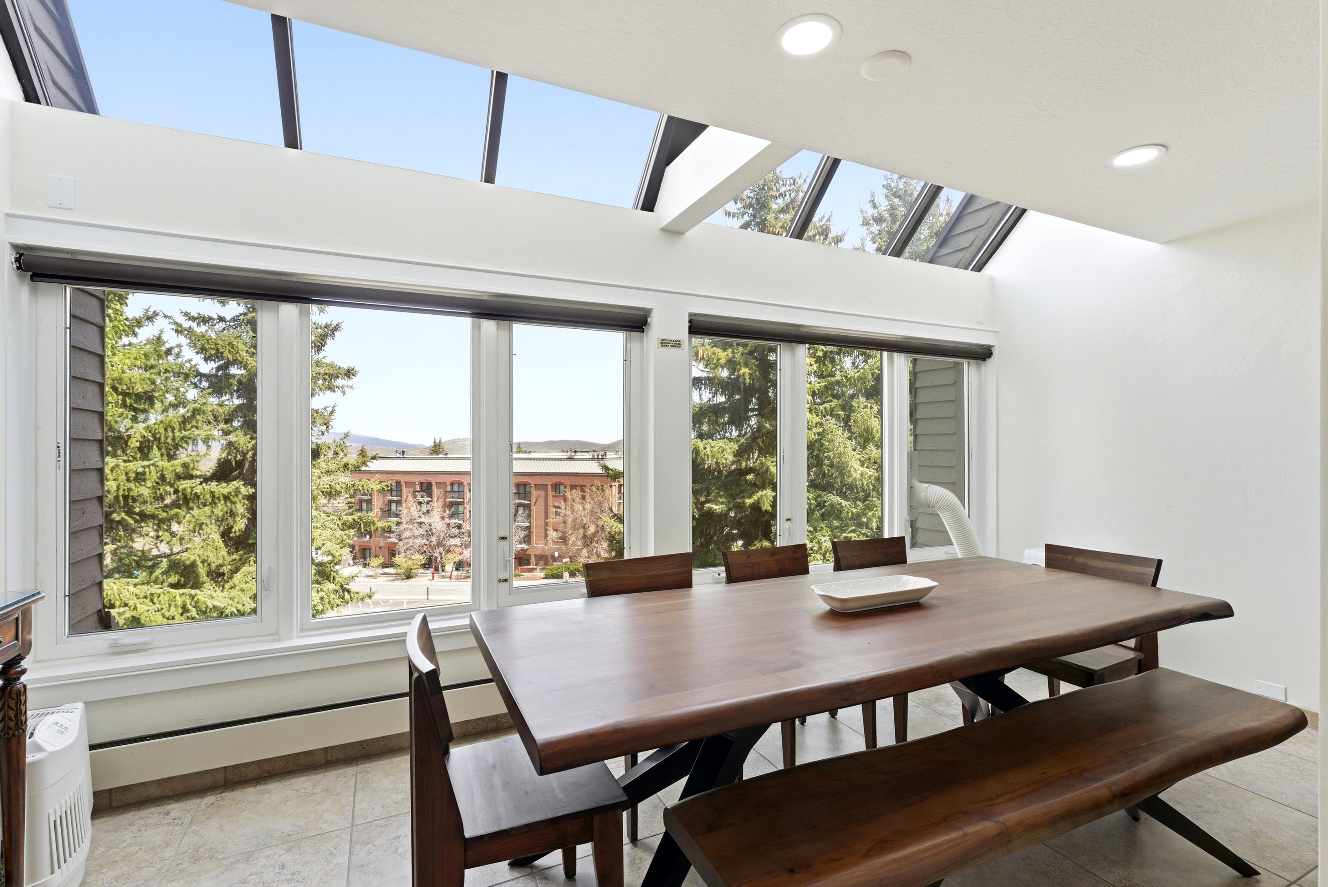 Dining room with a skylight, a baseboard radiator, recessed lighting, light tile patterned floors, and a high ceiling