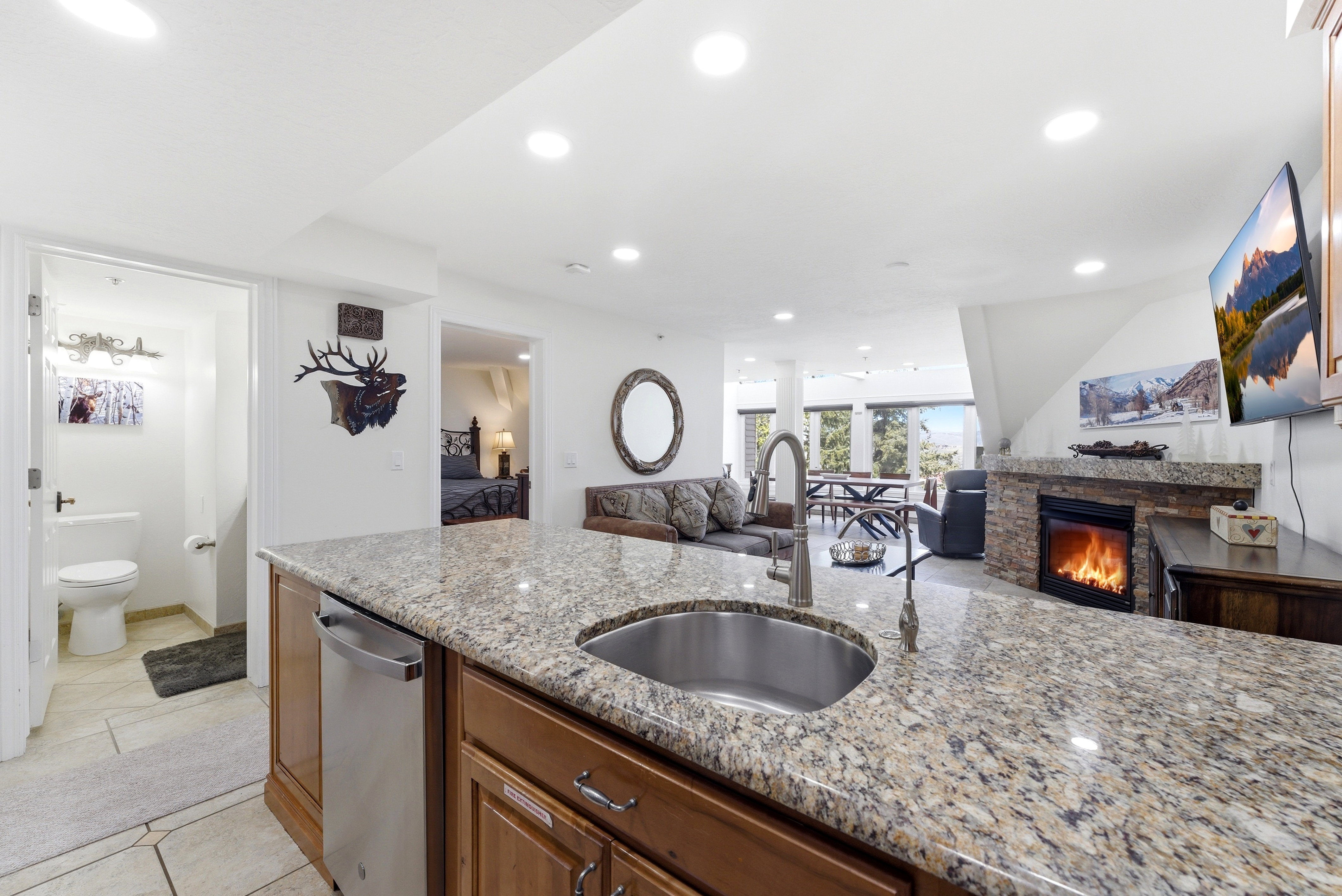 Kitchen featuring open floor plan, recessed lighting, light stone countertops, a glass covered fireplace, and light tile patterned floors
