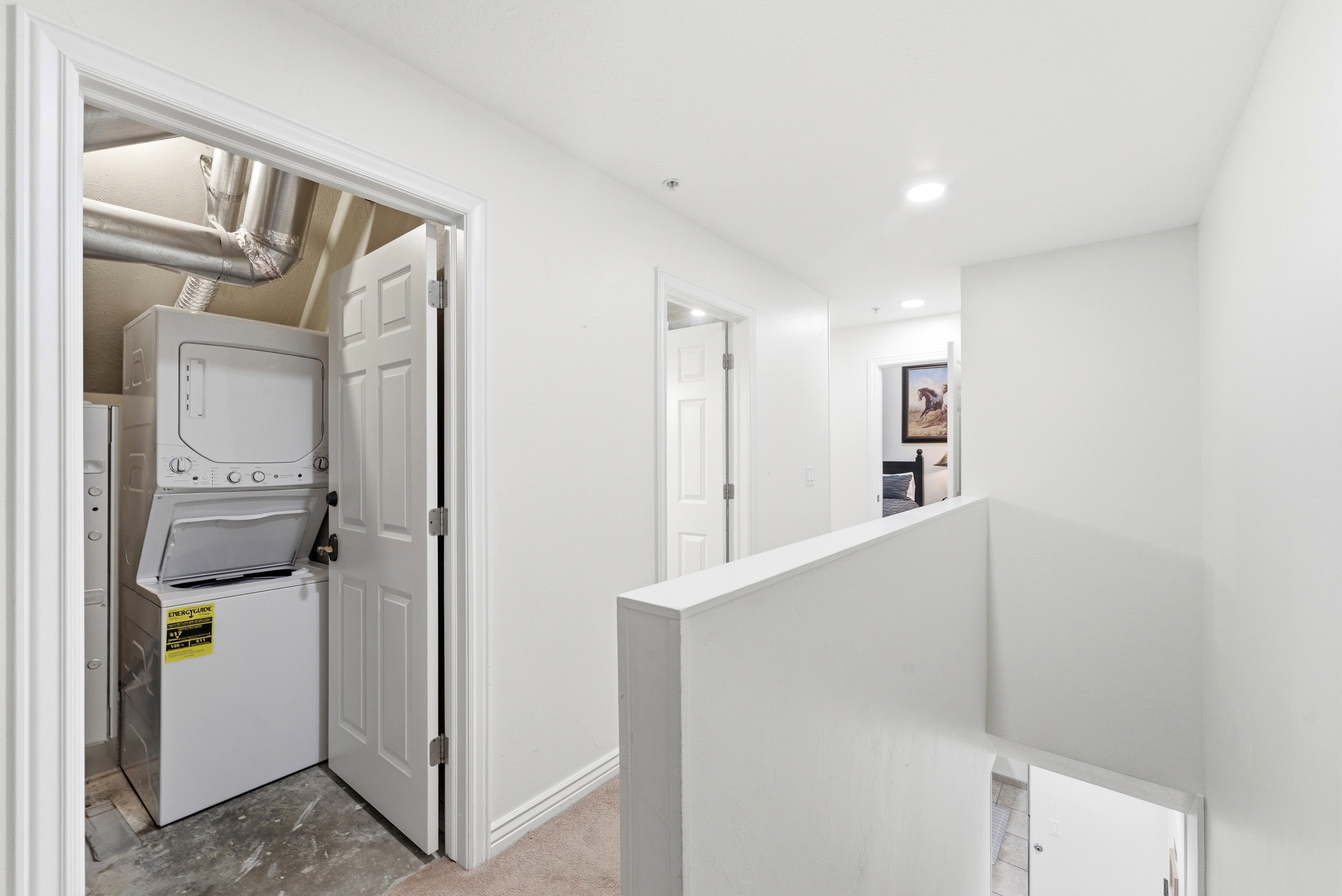 Laundry room featuring stacked washer and clothes dryer and recessed lighting