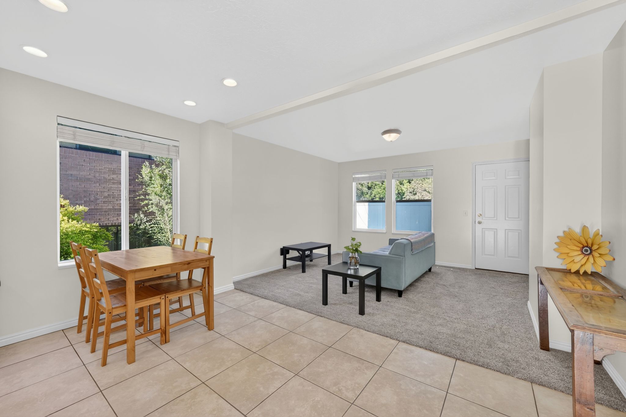Open-concept living area featuring tile flooring, recessed lighting, neutral paint, a paneled entry door, and a carpeted lounge area