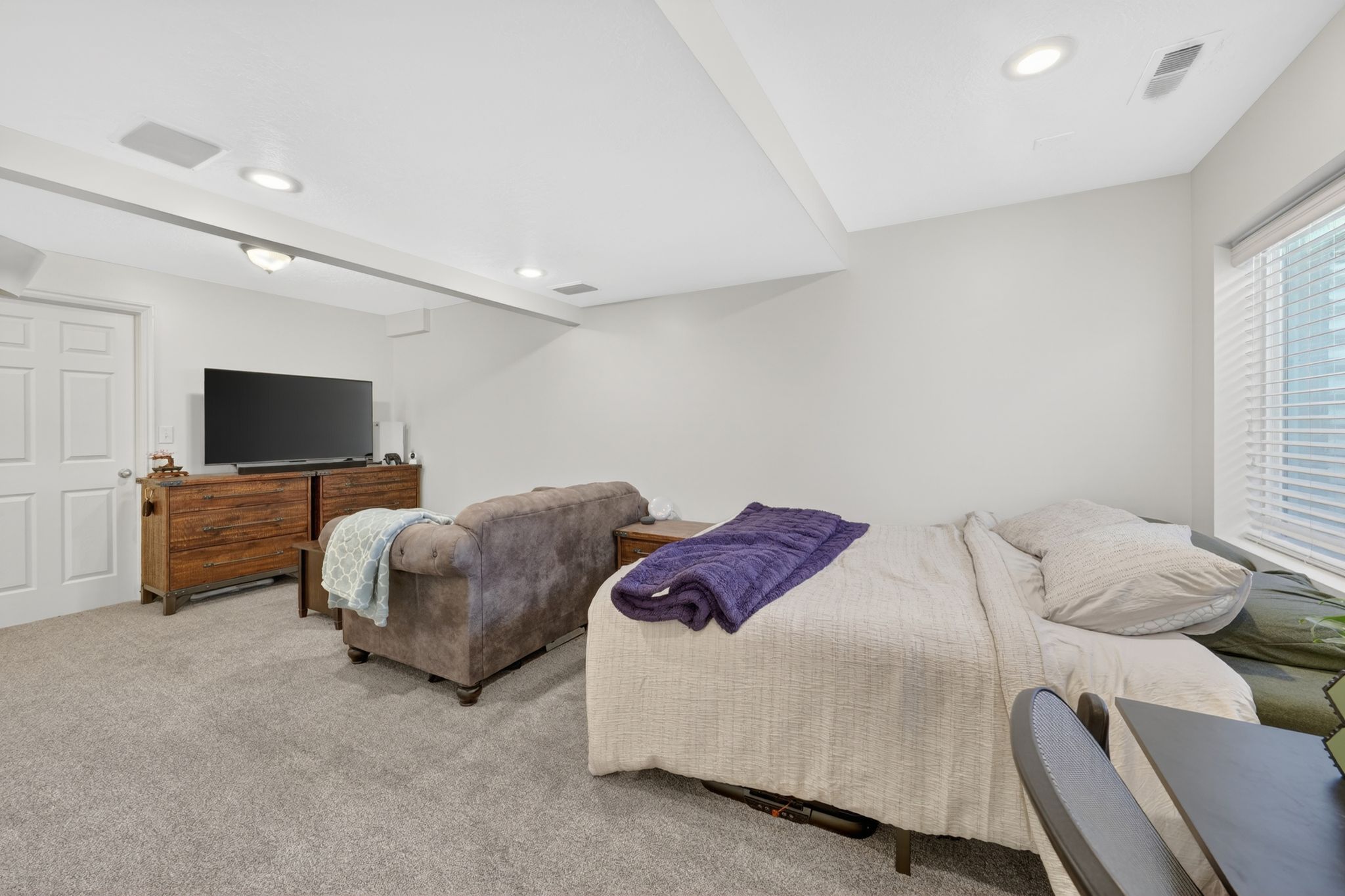 Basement carpeted room featuring recessed lighting and a window with blinds