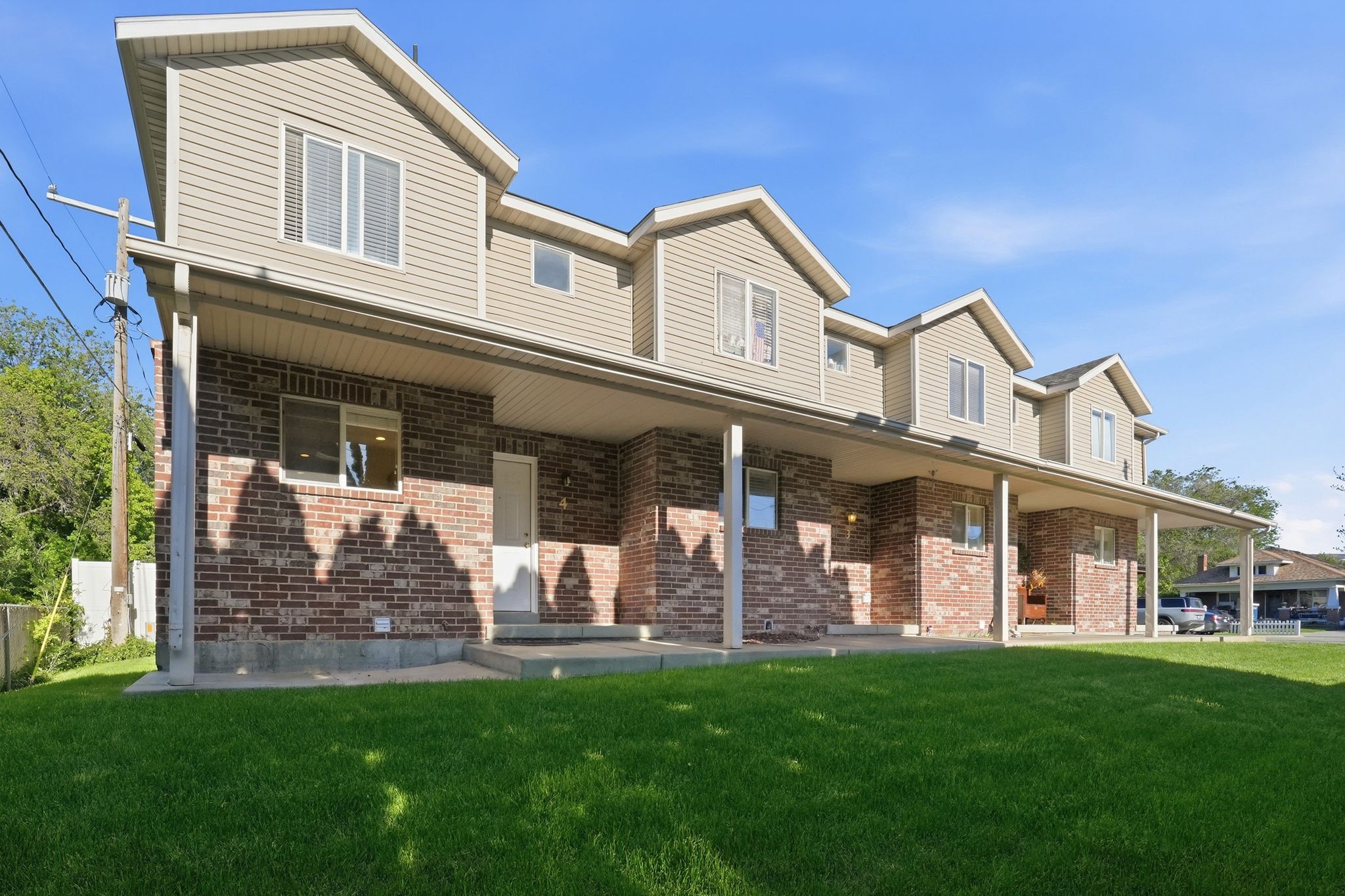 Multi-unit dwelling featuring brick and siding exterior, multiple gabled dormers, a covered front porch, and individual entry doors
