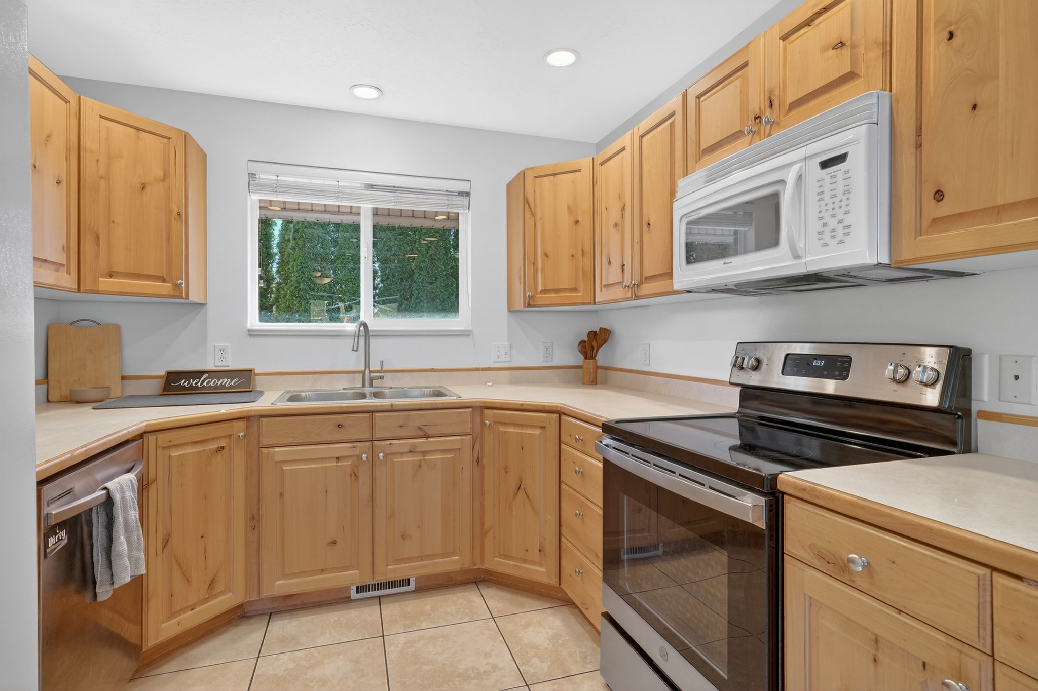 Kitchen featuring wood cabinetry, light-toned countertops, and a window above the double-basin sink