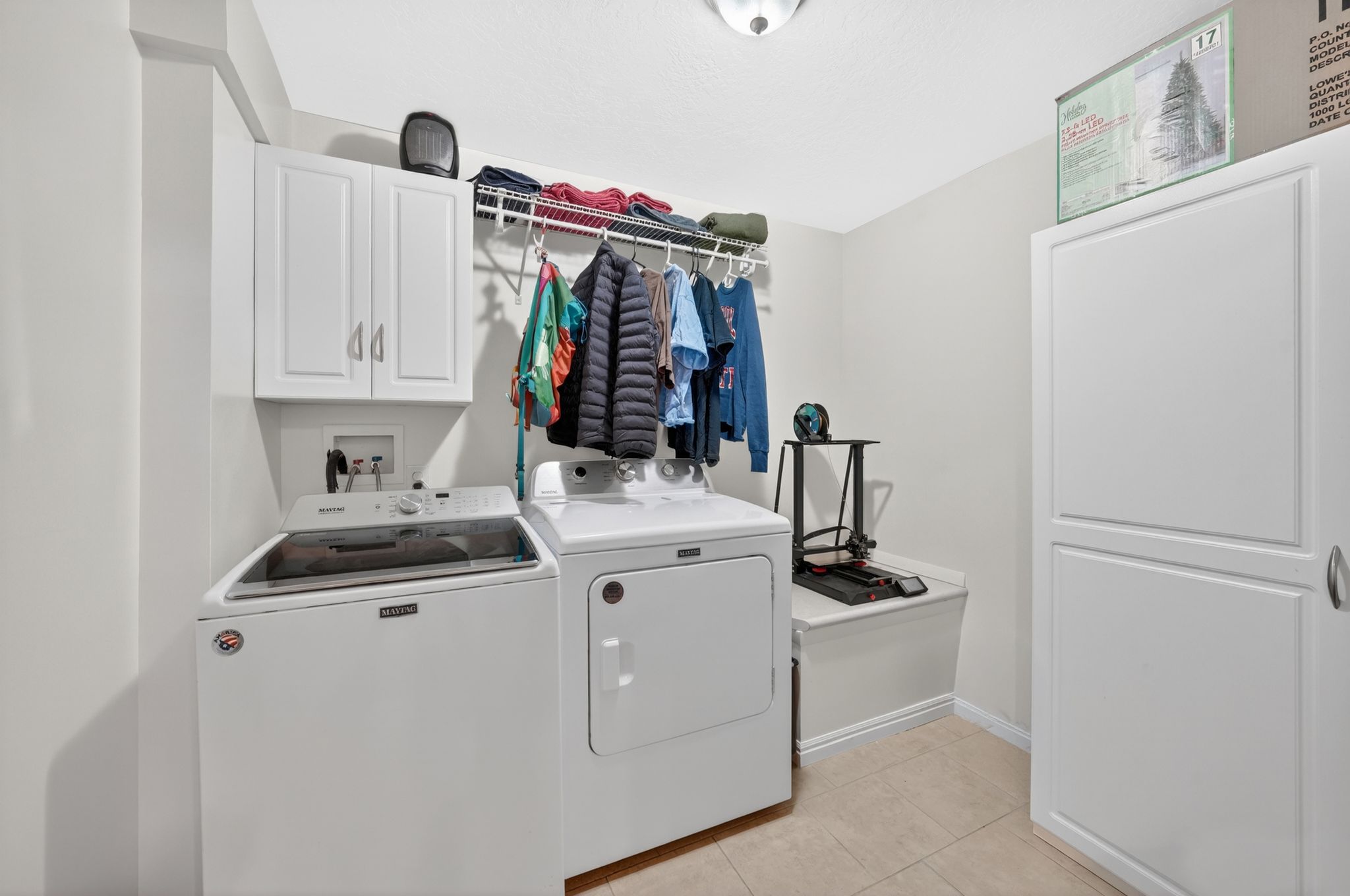 Laundry room featuring white cabinetry, a wire shelving system, a built-in bench, and tile flooring