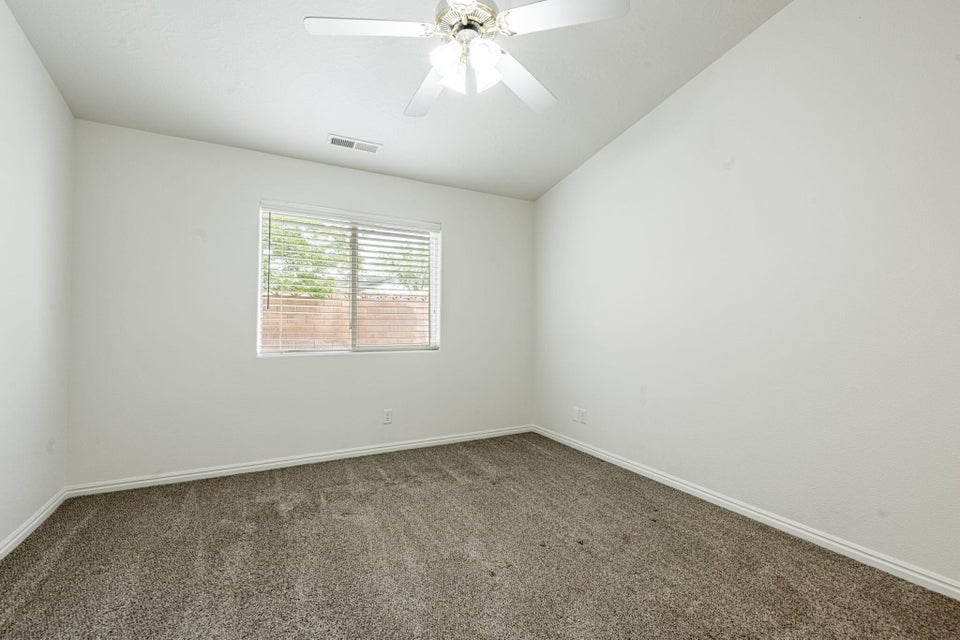 Carpeted interior room with white walls, a single window with horizontal blinds, and a ceiling fan with light fixture