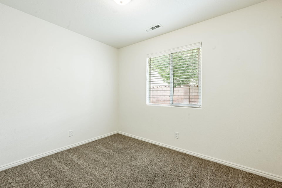 Neutral-toned room featuring a single window with horizontal blinds, textured wall finishes, a ceiling-mounted light fixture, white baseboards, and a carpeted floor