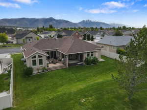 Expansive backyard featuring a large green lawn, a multi-level deck, and a sunroom with tall windows