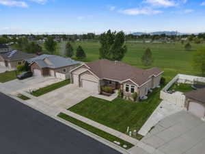 Ranch-style residence featuring a prominent two-car garage, stone and siding exterior, a manicured front lawn, and a paved driveway