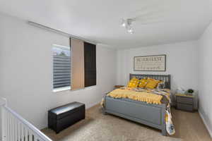 Carpeted room with white walls, featuring a window with horizontal blinds and sliding panel shades
