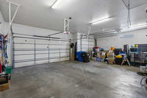 Spacious two-car garage featuring a concrete floor, white walls, and overhead fluorescent lighting