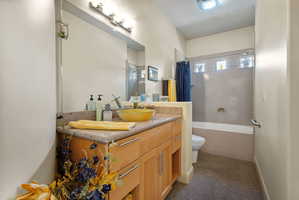 Bathroom vanity featuring a vessel sink, stone countertop, wood cabinetry, and a full-width mirror