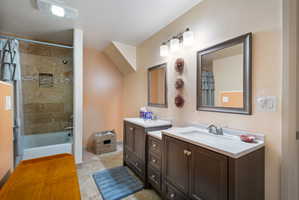 Full bathroom featuring a tub/shower combination with tile surround, dual vanity with undermount sinks, and ceramic tile flooring