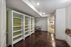 Expansive space featuring built-in white shelving, wood-finish flooring, recessed lighting, and a defined arched doorway
