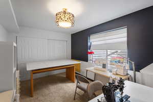 Room featuring textured carpet flooring, a decorative semi-flush mount ceiling light fixture, a window with horizontal blinds, and a built-in closet with panel-style bi-fold doors