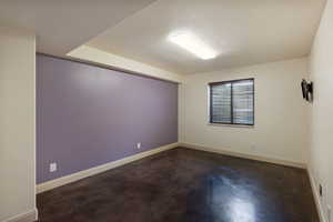 Spacious room featuring a deep purple accent wall, light-toned perimeter walls, and dark flooring