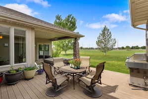 Expansive outdoor deck featuring wood-finish flooring, a covered patio area, and a built-in outdoor grill station