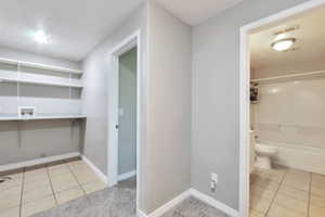Dedicated laundry area featuring tile flooring, built-in shelving, and utility hookups