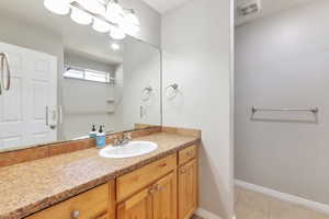 Bathroom vanity featuring a light-toned countertop, undermount sink, and wood cabinetry