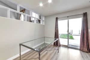 Interior space featuring wood-finish flooring, a full wall with integrated shelving, and recessed lighting