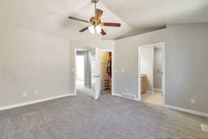 Spacious room featuring vaulted ceilings, light gray wall paint, and gray carpet flooring