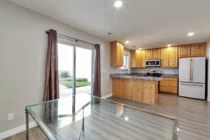Kitchen featuring light wood cabinetry, stone countertops, stainless steel appliances, and a tile backsplash