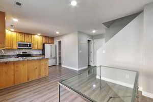 Kitchen featuring wood cabinetry, granite countertops, stainless steel appliances, and a mosaic tile backsplash