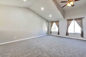 Spacious room featuring vaulted ceilings, recessed lighting, a ceiling fan, two windows, and neutral carpeting
