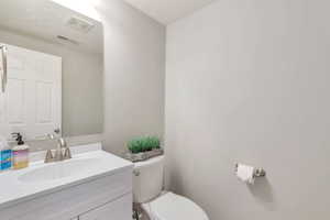 Modern bathroom featuring a white vanity with an integrated sink, brushed nickel faucet, large mirror, and a white toilet