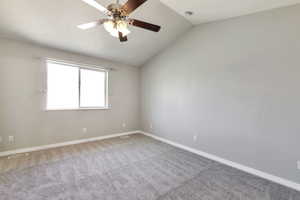 Spacious room featuring vaulted ceilings and a ceiling fan with integrated lighting