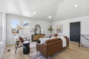 Spacious living area featuring light wood-finish flooring, recessed lighting, and a vaulted ceiling