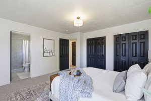 Carpeted bedroom featuring white walls and black paneled bi-fold closet doors